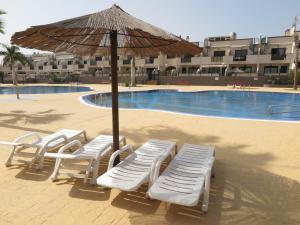 a group of chairs and an umbrella next to a pool at Los Geranios 21 Tenerife in Costa Del Silencio