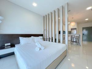 um quarto com uma grande cama branca com almofadas brancas em Mercu Summer Suites KLCC by Veedu Hauz em Kuala Lumpur