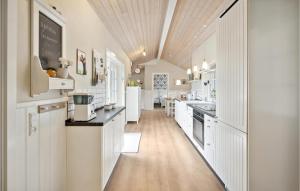 ArrildにあるBeautiful Home In Toftlund With Wifiの白いキャビネットと木製の天井が備わるキッチン
