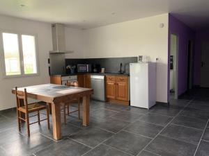 cocina con mesa de madera y nevera blanca en Les Enfants du Marais, en Favières