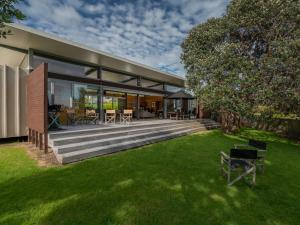 a house with a large deck and a yard at Little Paua - Pauanui Holiday Home in Pauanui