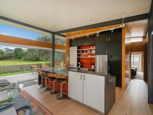 an open kitchen with a table and a large window at Little Paua - Pauanui Holiday Home in Pauanui