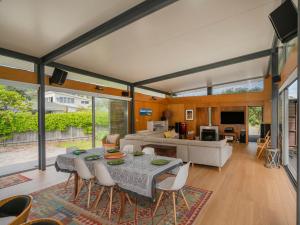 a dining room and living room with a table and chairs at Little Paua - Pauanui Holiday Home in Pauanui