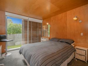 a bedroom with a bed and a large window at Little Paua - Pauanui Holiday Home in Pauanui