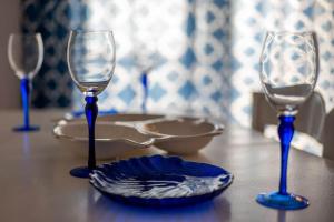 three wine glasses and a plate on a table at Meli Apartments near sea side in Kythira