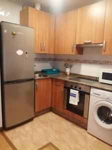 a kitchen with a stainless steel refrigerator and a dishwasher at Apartamento con terraza a 800 m playa in Gijón