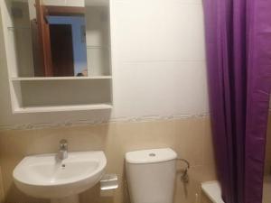 a bathroom with a sink and a toilet and a mirror at Apartamento con terraza a 800 m playa in Gijón