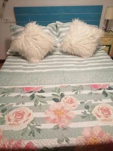a bed with two pillows with pink flowers on it at Apartamento con terraza a 800 m playa in Gijón