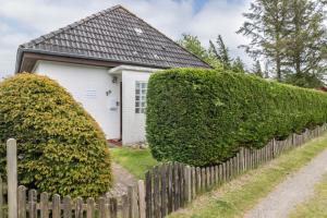 a house with two large hedges in front of a fence at Ferienhaus Herich in Nieblum