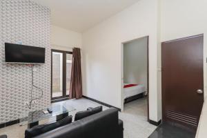 Una sala de estar con un sofá y un televisor en una pared. en RedDoorz Syariah near Green Park Jatiwarna, en Bekasi