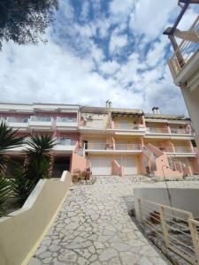 un gran edificio de apartamentos de color rosa con un patio de piedra en Seaside house, en Vrachos