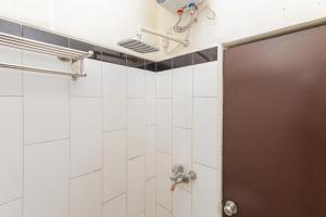 a bathroom with a shower with white tiles at RedDoorz Syariah near Green Park Jatiwarna in Bekasi