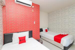 two beds in a room with a brick wall at RedDoorz Syariah near Green Park Jatiwarna in Bekasi