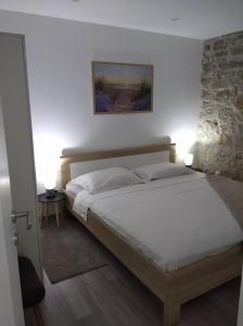 1 dormitorio con 1 cama grande y pared de piedra en Apartman Lari, en Vižinada