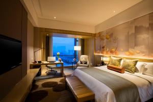 Crowne Plaza Fuzhou Riverside, an IHG Hotel في فوتشو: غرفه فندقيه بسرير ومكتب ونافذه