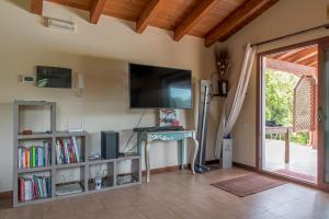uma sala de estar com uma televisão e uma porta de vidro deslizante em Countryside villa with pool em San Sperate