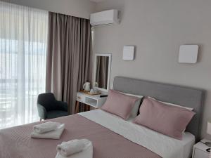 una camera da letto con un letto con cuscini rosa e una sedia di Hotel Avra a Preveza