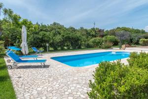 uma piscina com duas espreguiçadeiras e um guarda-sol em Countryside villa with pool em San Sperate