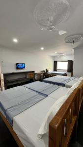 2 camas en una habitación con TV en la pared en ANAND Beach Guesthouse by Moonrocks, en Mahabalipuram