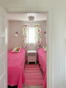 twee bedden in een kleine kamer met roze lakens bij Strandbergs Stugor in Mariehamn