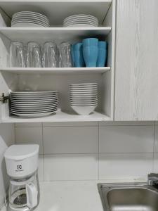 un armario de cocina con platos y cuencos y un fregadero en Northern Lights - Cozy apartment, en Kalajoki