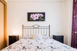 a bedroom with a bed with a flower picture on the wall at Apartamento céntrico Candás in Candás