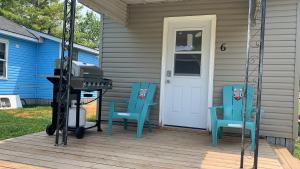 two blue chairs sitting on a porch with a grill at Snug Harbour Cottage and Marina in Kawartha Lakes