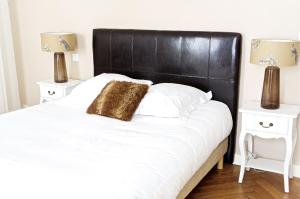 een slaapkamer met een groot wit bed met een zwart hoofdeinde bij Louis Combes - Appartement 1 chambre avec parking in Bordeaux