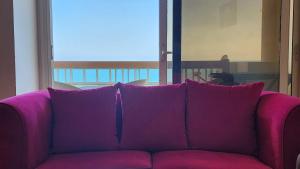 Midpoint Sea View - families only في الإسكندرية: أريكة أرجوانية تجلس أمام النافذة