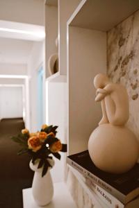 a doll sitting on top of a book next to a vase at Sol Hotel in Shkodër