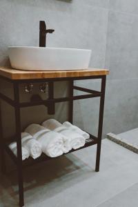 un bagno con lavandino e asciugamani su una mensola di Sol Hotel a Shkodër