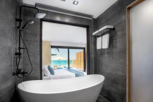 X Eastern Sidi Abdel Rahman Hotel في العلمين: حمام مع حوض استحمام ومنظر لغرفة النوم