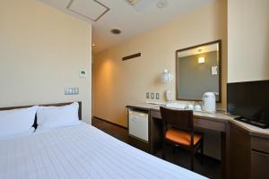 Pokój hotelowy z łóżkiem, biurkiem i lustrem w obiekcie Wakayama Daini Fuji Hotel w mieście Wakayama