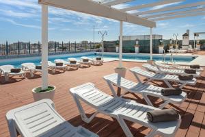 une terrasse avec des chaises longues et une piscine dans l'établissement Exe Sevilla Macarena, à Séville