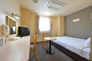 a hotel room with a bed and a table and a tv at Wakayama Daini Fuji Hotel in Wakayama