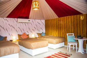 a bedroom with two beds and a table with a table at Desert Season Camp in Wadi Rum