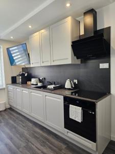 a kitchen with white cabinets and a black counter top at Galaxy Apartments 2 in Słupsk