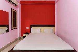 Ce lit se trouve dans une chambre dotée d'un mur rouge. dans l'établissement SPOT ON 81399 Hotel Rainbow Regency, à Rourkela