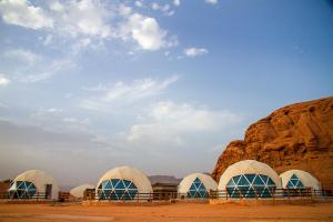 Desert Season Camp في وادي رم: مجموعة من القباب في الصحراء مع صخرة