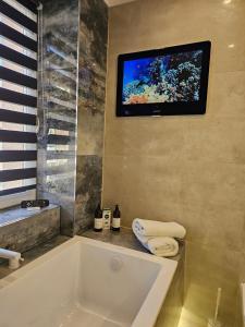 a bathroom with a tub and a tv on the wall at Galaxy Apartments 2 in Słupsk