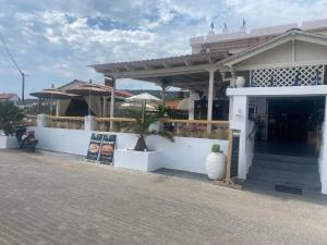 a white building with a porch and a white wall at Hotel Beach Amaryllis in Megalochori