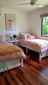 Duas camas num quarto com pisos em madeira em Moogie House em Moogerah