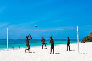 a group of men playing volleyball on the beach at Diamonds Leisure Beach & Golf Resort in Diani Beach