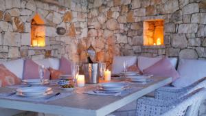 una mesa con platos y velas en una pared de piedra en Villa Flora, en Oziás 3 fotos más