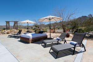 a bed and chairs and umbrellas on a patio at Quiet Compound 5Min to Park Pool and Spa 5Acres in Joshua Tree