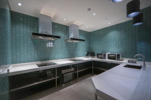 una cocina con paredes de azulejos verdes y electrodomésticos de acero inoxidable. en Tulu Apartment Shanghai Xuhui en Shanghái