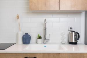 a white kitchen counter with a sink and a kitchen appliance at דירת סטודיו מודרנית מול החוף By Edomlux in Eilat