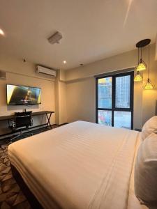 Hotel Aman Kuala Lumpur في كوالالمبور: غرفة نوم بسرير ابيض كبير وتلفزيون بشاشة مسطحة