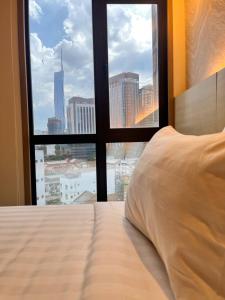 a bed with a view of a city from a window at Hotel Damai Kuala Lumpur in Kuala Lumpur