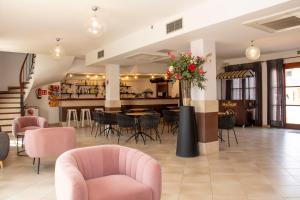 Un restaurante con sillas rosas y una mesa con flores. en Grupoandria Aparthotel Club Andria, en Cala Santandria